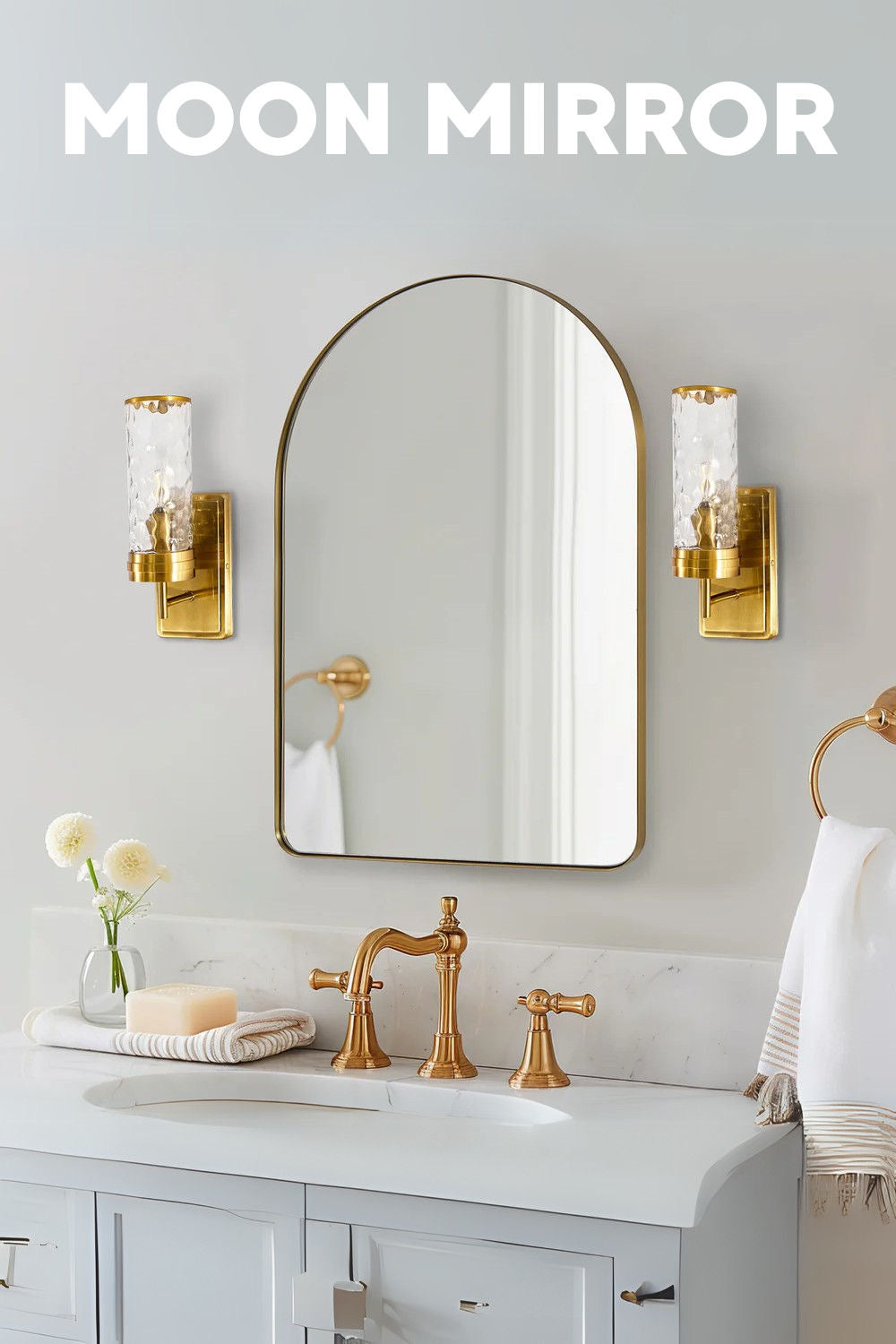 “Elegant bathroom vanity with a white countertop, gold faucets, and an arched mirror framed in brass. Flanking the mirror are textured glass sconces, creating a refined and classic look.”
